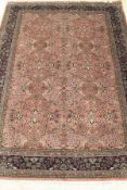 A Persian carpet, the central panel set with all over floral decoration on a pale pink ground,