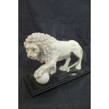 A reconstituted marble figure of a lion with paw on ball