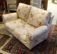 A modern floral upholstered scroll arm two seat sofa on turned legs to brass caps and castors