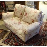 A modern floral upholstered scroll arm two seat sofa on turned legs to brass caps and castors