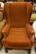 An early 20th Century wing back arm chair in the 19th Century manner and orange upholstery