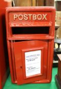 A red painted metal postbox inscribed "Postbox"