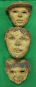 A set of three fired clay wall pockets of facial design,