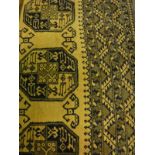A Bokhara rug, the central panel set with repeating medallions on a mustard / gold ground,