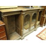 An oak breakfront bookcase with two arch glazed cabinet doors flanked with adjustable shelves on a