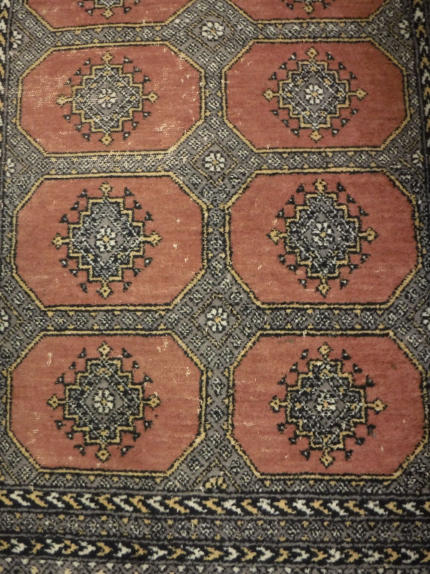 A Persian rug, the central panel set with repeating medallions on a mushroom ground,