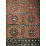 A Persian rug, the central panel set with repeating medallions on a mushroom ground,