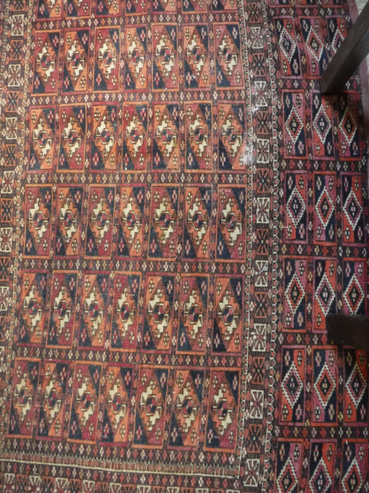 A Bokhara Torba rug, the main panel set with repeating tile design on a dark red ground,