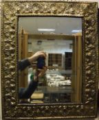 An early 20th Century bevelled mirror with embossed brass frame depicting shells