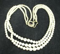 A graduated pearl three strand necklace with nine carat gold mounted seed pearl and garnet clasp