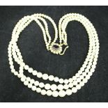 A graduated pearl three strand necklace with nine carat gold mounted seed pearl and garnet clasp