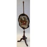 A Victorian walnut framed pole screen with needlework upholstered panel raised on a tripod base