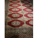 A Bokhara rug, the central panel set with repeating medallions on a red and blue ground,