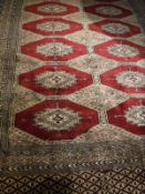 A Bokhara rug, the central panel set with repeating medallions on a red and blue ground,