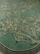 An Art Deco Chinese rug, the central panel set with prunus blossom branches on a green ground,