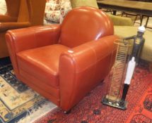 A modern red leather upholstered armchair in the Art Deco style together with a Blackamoor CD rack