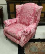A modern upholstered wing back scroll arm chair in the 19th Century manner