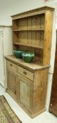 A pine dresser, the two tier boarded plate rack over two drawers and two cupboard doors,