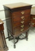 An Edwardian mahogany music cabinet of five fall front drawers on turned legs in the William and