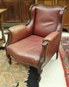 A circa 1900 mahogany framed red leather upholstered wing back fireside chair with acanthus carved