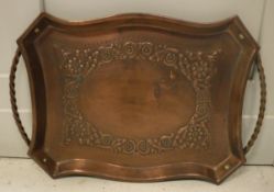 An Arts & Crafts style copper twin-handled tray with embossed scrolling foliate decoration,