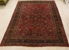 A Mashad carpet, the central panel set with all over floral decoration on a plum ground,