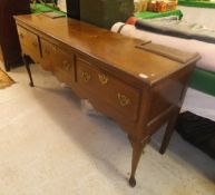 A 19th Century North Country oak and cross-banded dresser base of three drawers on cabriole legs,