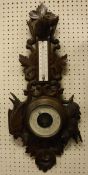 A Black Forest type carved wooden framed barometer / thermometer,