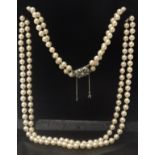 A vintage double strand faux pearl necklace with decorative clasp and safety chain,