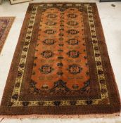An Afghan rug, the central panel set with repeating medallions on a rust ground,