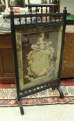 A late Victorian ebonised fire screen in the aesthetic manner with needlework panel of an armorial