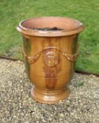 A modern glazed terracotta garden urn in the 19th Century manner set with floral swags and heraldic