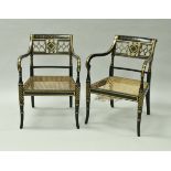 A pair of ebonised and gilt decorated open scroll arm elbow chairs with cane seats in the Regency