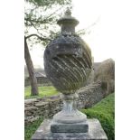 A carved reconstituted stone garden urn or finial of wrythen stop fluted form,