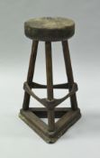 A 19th Century treenware stool with circular block seat on three splayed chamfered supports united