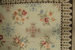 An Aubusson style rug the central panel set with floral sprays on a mushroom ground within a
