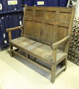 A 19th Century stained pine settle, the panelled back over open scroll arms over a plank seat,