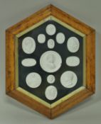 A maple framed and glazed elongated hexagonal collection of thirteen plaster bust medallions in the