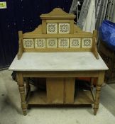 A pine washstand with tiled back and grey veined white marble top over a central cupboard door