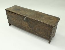 An 18th Century elm coffer the top with moulded decoration and notch carved ends bearing