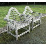 A pair of teak Lutyens style slatted scroll arm chairs and a slatted teak two tier garden table