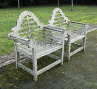 A pair of teak Lutyens style slatted scroll arm chairs and a slatted teak two tier garden table