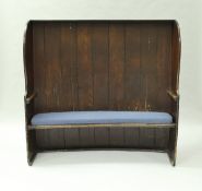 A 19th Century oak barrel back tavern settle with shaped wing sides and single piece plank seat,