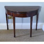 A Regency mahogany fold over card table of demi-lune form the satinwood cross banded top opening to