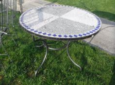 A tile top circular garden table and a set of eight wrought iron chairs with slatted backs and