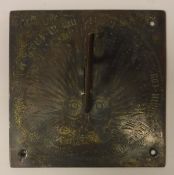 A gilt bronze sundial with central smiling sunburst within Roman numerals and script,