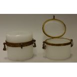 A pair of early 19th Century French milk glass oval lidded boxes with gilt brass type mount