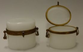 A pair of early 19th Century French milk glass oval lidded boxes with gilt brass type mount