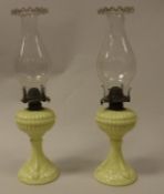 A pair of Victorian yellow milk glass oil lamps and chimneys with crimped rim and a blue milk glass