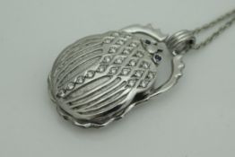 An unmarked 18 carat white gold pendant in the form of a scarrab beetle with diamond studded back